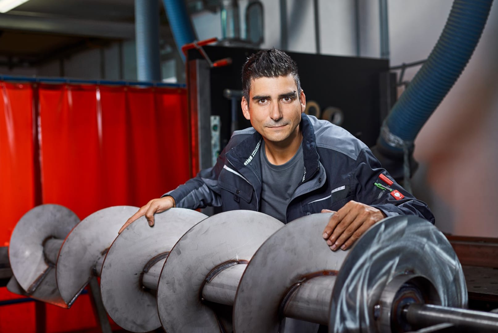 Mitarbeiter mit einer großen Förderschnecke in der Produktion